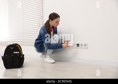 Woman with screwdriver installing new socket at home Stock Photo