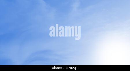A soft, blurred light blue background featuring subtle cloud-like textures and a bright, gentle white sunlight glow. Stock Photo