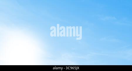 A soft, blurred light blue background featuring subtle cloud-like textures and a bright, gentle white sunlight glow. Stock Photo