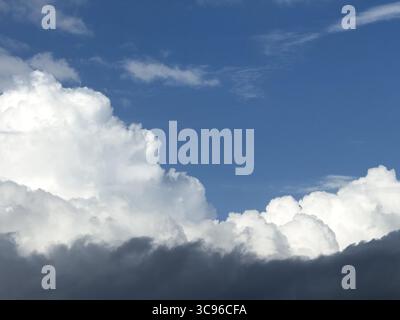 At the bottom of the picture grey nimbostratus clouds, above white cumulus cumulus clouds in front of a blue sky, International Stock Photo