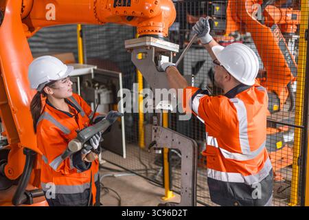 technician engineer team fix service maintenance inspection automatic robot arm machine installation in modern factory. workers check adjusting repair Stock Photo