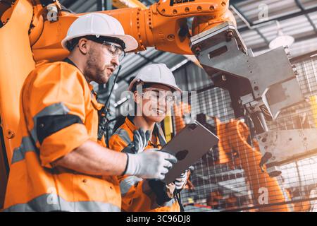 Engineer team service robot welding working in automation factory. People workers safety work control robot machine in heavy industry technology. Stock Photo