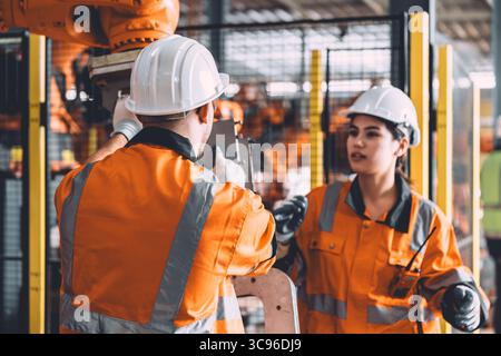 Engineer team service robot welding working in automation factory. People workers safety work control robot machine in heavy industry technology. Stock Photo