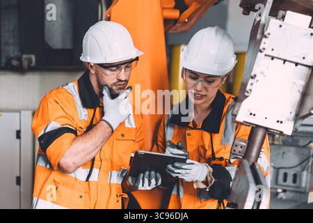 Engineer team service robot welding working in automation factory. People workers safety work control robot machine in heavy industry technology. Stock Photo