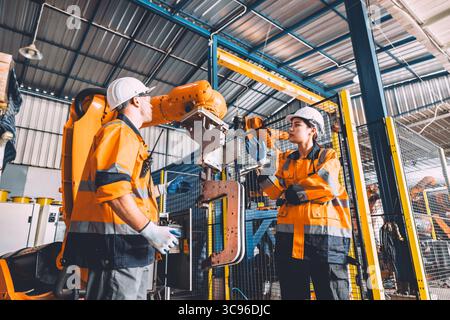 Engineer team service robot welding working in automation factory. People workers safety work control robot machine in heavy industry technology. Stock Photo
