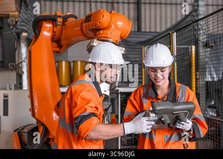 Robotic technician engineer male training helping young women team control operate robot welding arm in modern automated industry factory Stock Photo