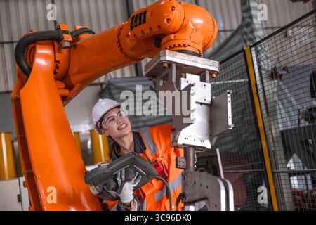 Technician engineer women test control operate inspection robot arm installation in factory. worker check adjusting robot with controller device. Stock Photo