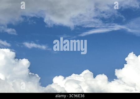 Below white cumulus clouds Cumulus clouds above grey stratocumulus framing blue sky, international Stock Photo