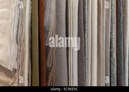 A collection of various fabric swatches in neutral tones. The fabrics include linen, cotton, and silk, arranged neatly in vertical rows. Stock Photo