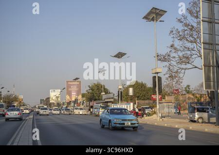 Lusaka, Zambia - 17 August 2022: View of a sun-drenched Zambian street, where the dusty road mirrors the clear sky, lined with solar-powered lamps and Stock Photo