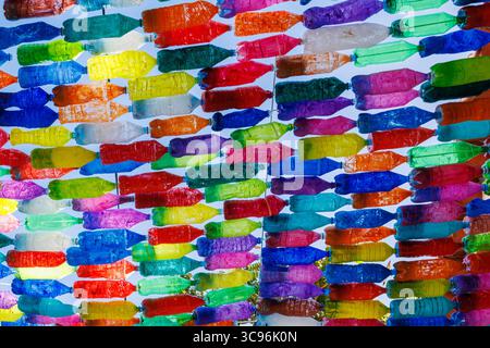 Brightly painted plastic bottles strung together as street decorations. Homemade garlands of colored bottles on Madeira Island, Portugal. High quality Stock Photo