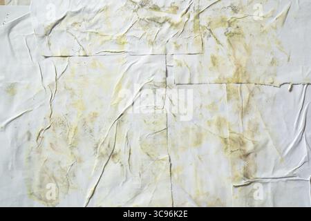 Dirty white wheatpaste paper poster texture on wall with yellow stain Stock Photo