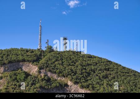 Telecommunication towers standing on a verdant hilltop against a clear blue sky, ensuring connectivity in the italian countryside Stock Photo
