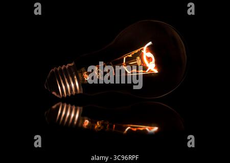 Glowing light bulb without wires on black background. Stock Photo