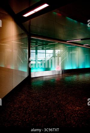 An interior shot of a modern building with a glass wall and a staircase visible through the glass. The lighting is a mix of natural and artificial, wi Stock Photo