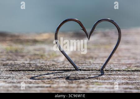 Heart Shape Made of Two Fish Hooks on wood Stock Photo