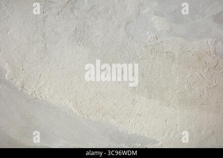 Textured white wall with imperfections, ideal for backgrounds and design elements. Features a rough plaster surface. Stock Photo