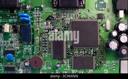 Complex design of an electronic circuit board showcasing intricate components and connections in vivid detail and bright lighting. Stock Photo
