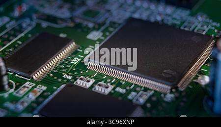 A close-up view captures detailed components of a circuit board, emphasizing connections and microchips on a green surface. Stock Photo