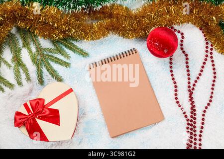 Message to Santa Claus. Christmas fir tree branches on wooden board with blank notebook with spangle, christmas ball and giftbox on snow. Christmas or Stock Photo