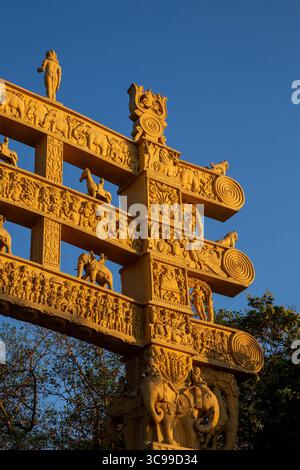 Ornate ancient gateway with intricate stone carvings and figures, photographed under clear blue sky, representing Indian heritage Stock Photo