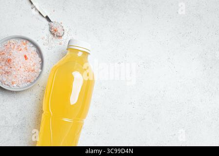Orange Isotonic energy drink. Bottle of homemade yellow sport electrolyte water with hymalayan salt on white background, top view, copy space. Fitness Stock Photo