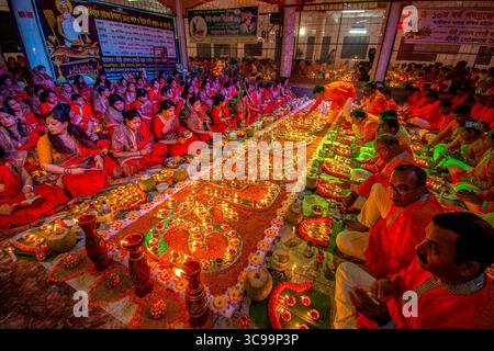 Dhaka, Bangladesh - 13 November 2018: View of a long table covered with candles and decorations, surrounded by people in red and orange attire at the Stock Photo