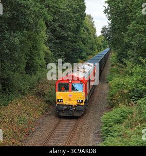 A DB Cargo’s locomotive, no 66067, has just left Rainford junction station as it approaches Birches Occupation Bridge to the west of Rainford station Stock Photo