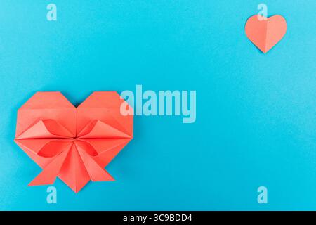 Red origami hearts on a blue background, a celebration of love and craftsmanship. Stock Photo