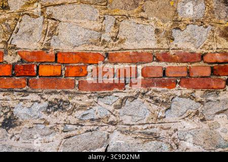 Detailed view of an old wall combining rough stone and red bricks, showcasing craftsmanship and the passage of time in architectural materials. Stock Photo