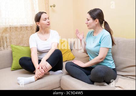 Two women having a serious conversation on couch, support and communication concept Stock Photo