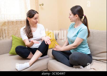 Two women having a serious conversation on couch, support and communication concept Stock Photo