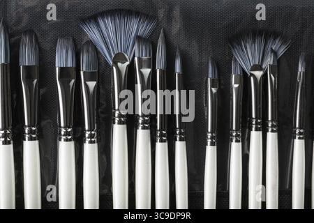 A set of oil brushes and palette knife isolated on a black background, Close-up Stock Photo