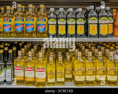 Italy - August 5, 2025: Olive oil of various brands in glass bottles displayed on shelves in an Italian supermarket. Stock Photo