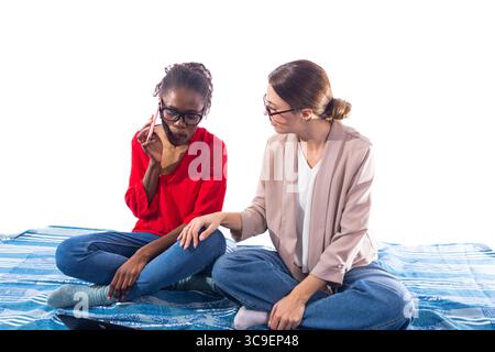 Two young women working remotely using smartphone and laptop Stock Photo
