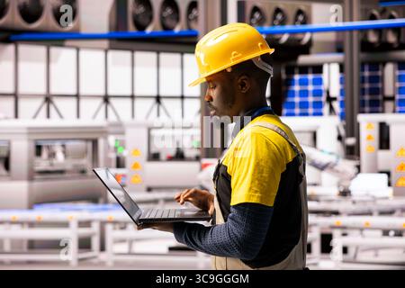 Industrial technician manages automated production line with robotic arms and digital systems. The smart manufacturing plant employs continuous maintenance and automation for innovative output. Stock Photo