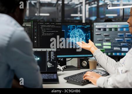Engineering team inspecting neural network data center used for machine learning. Teamworking colleagues doing maintenance on server hub to optimize it for artificial intelligence workloads Stock Photo