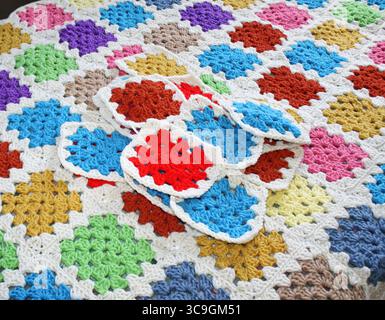 Colorful handmade crocheted granny squares laying on the surface of completed blanket that has been put together after joining the many squares Stock Photo