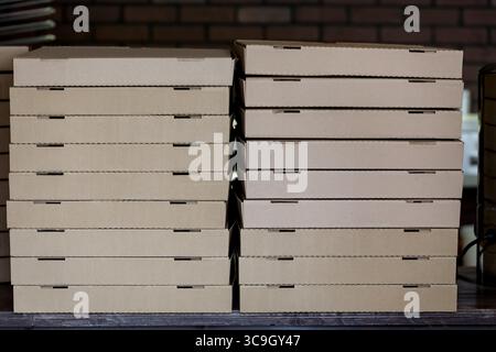 Stack of brown pizza boxes in pizzeria. Stock Photo