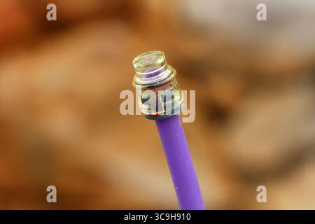 Detailed macro of a fiber optic cable with a clear connector tip, showing modern telecommunications technology in sharp focus against a blurred Stock Photo