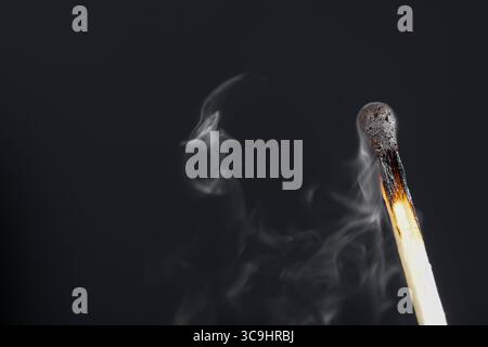 Extinguished match close up with smoke on dark background Stock Photo