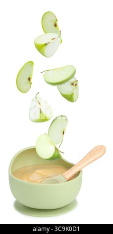 Baby food. Apple slices falling into bowl of puree on white background Stock Photo