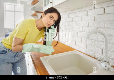 Woman calling to plumber, seeking immediate help with clogged sink Stock Photo