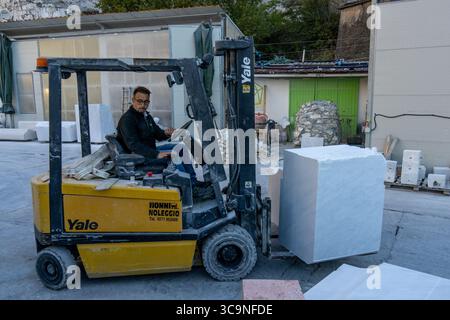 Worker at a marble carving studio moving a block of marble with a forklift. Fantiscritti, Carrara, Italy. Stock Photo