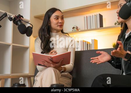 Podcast Recording. Engaging conversation between two women in a creative workspace. Stock Photo