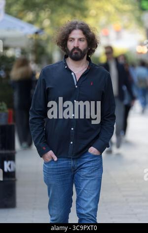 Young bearded man walking on the street with hands in his pockets Stock Photo
