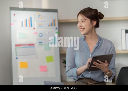 Professional woman analyzing data with tablet in modern office Stock Photo