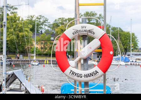 Stockholm, Sweden - July 9, 2025: Close-up view of a classic red and white lifesaver ring with the inscription Kastellholmen , mounted near the water Stock Photo