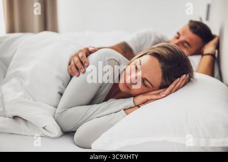 Young couple is sleeping in their bed. They are embracing and enjoying good sleep. Stock Photo