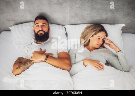 Couple is lying in bed. They are angry and not talking to each other. Stock Photo